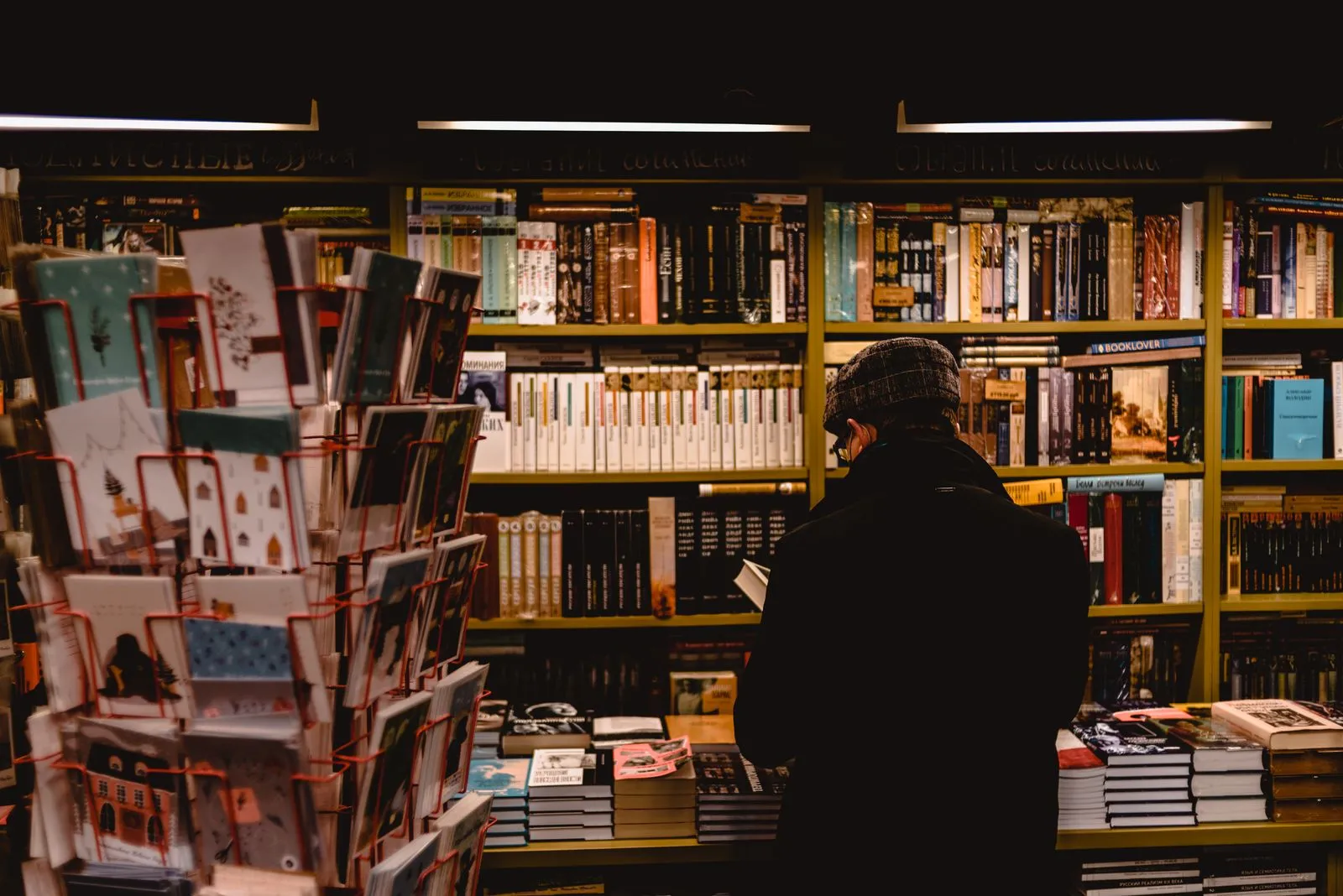 Individual browsing books in a cozy Saint Petersburg bookstore, offering a warm literary atmosphere.